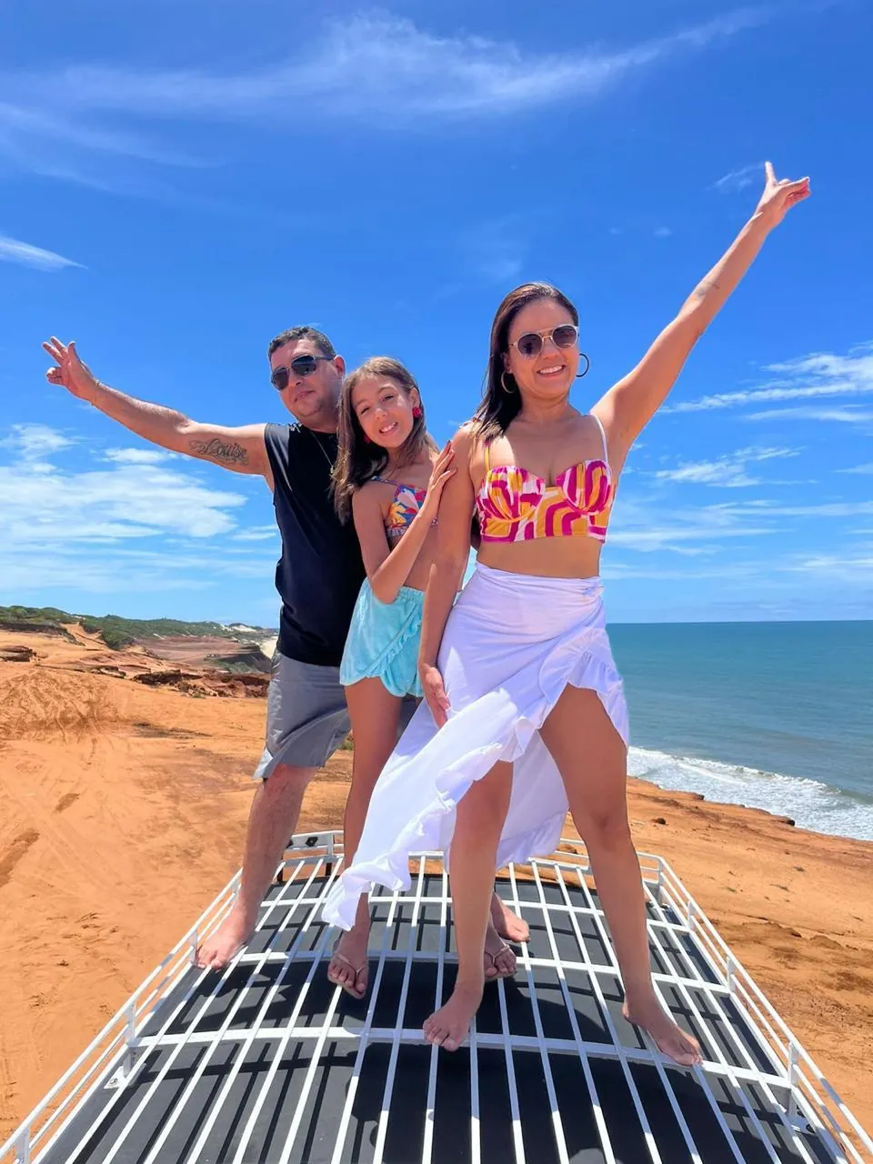 Família sobre o Jeep com vista para o litoral