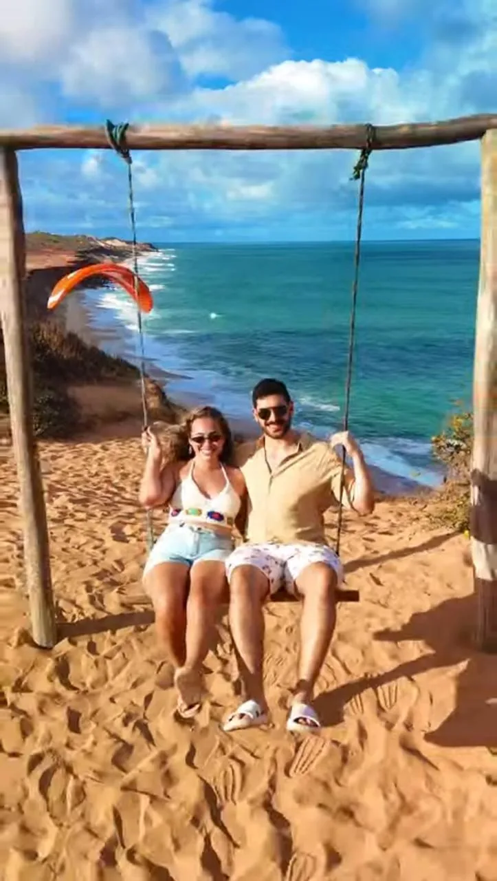 Casal no balanço com vista para o mar durante o passeio de quadriciclo